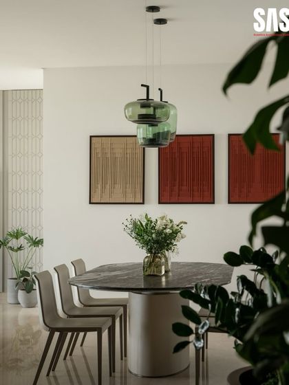The dining area at Embassy Lake Terraces is anchored by a stunning marble-topped table and handblown green glass pendant lights. These elements work together to define the space, creating an intimate setting for meals that is complemented by the earthy tones of the wall art.