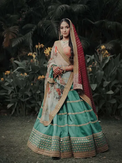 A full-length portrait of the bride in her stunning multi-colored Sangeet outfit. Her confident pose and the beautiful garden setting make for a striking and memorable image.