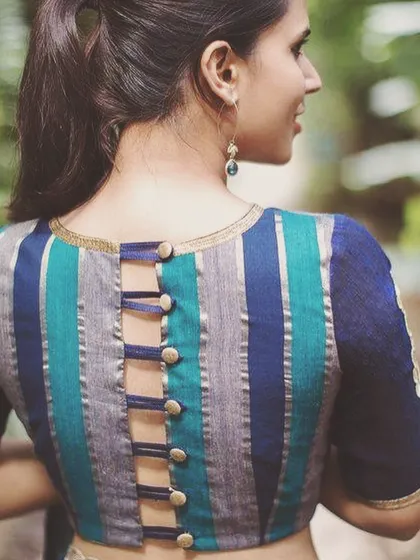 I enjoy creating unique blouse designs, like this striped boat neck blouse with a buttoned strap back. This is a great example of how we can add a modern twist to a classic saree look.