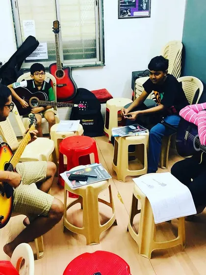 An interactive guitar lesson in progress. The small group size allows for personalized attention from the coach while still fostering a sense of community and peer learning.