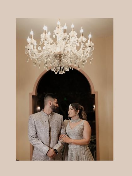 A beautifully composed portrait of the couple under a chandelier. Their loving gaze and the warm, elegant lighting create a timeless and romantic image.