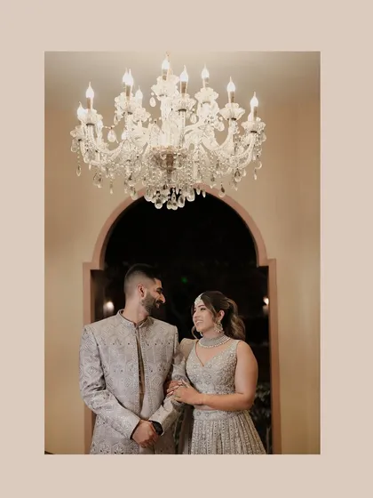 A beautifully composed portrait of the couple under a chandelier. Their loving gaze and the warm, elegant lighting create a timeless and romantic image.
