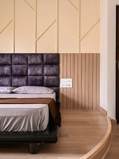 Here, I combined different textures and patterns for the bed's back wall. A plush, dark purple tufted headboard is paired with light wood fluted panels and a wall with geometric molding for a rich, layered effect.