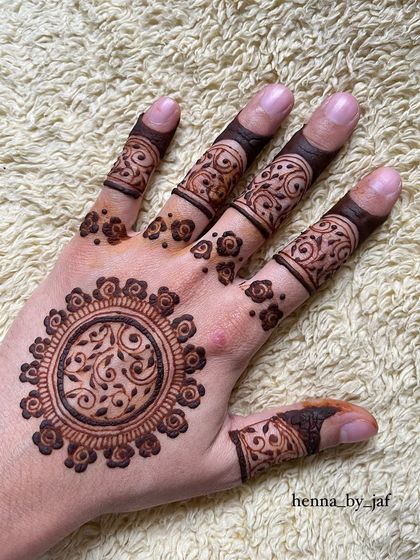 The same beautiful mandala design, but placed on the palm of the hand. The intricate details of the central vine pattern are clearly visible.