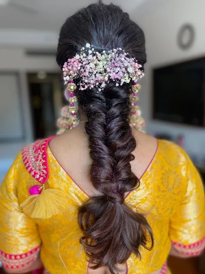 A messy fishtail braid adorned with a crown of colorful baby's breath. This is a beautiful bohemian look for a mehendi or haldi ceremony.