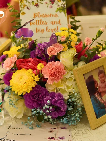 A vibrant floral centerpiece from a 'Wildflower' baby shower. The mix of colors and textures, along with a personalized photo, made each table feel unique and full of life.