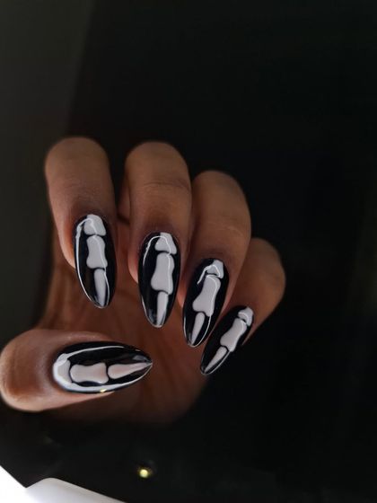 Spooky season is my favorite time to get creative. These Halloween nails feature a glossy black base with hand-painted, 3D-effect skeleton bones on long almond-shaped extensions for a look that's chic and creepy.