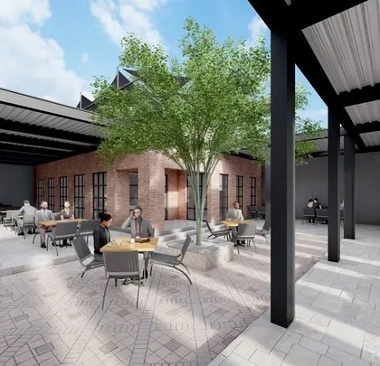 A wider view of the cafe's central courtyard, designed to be a social hub. The layout provides a mix of open and covered seating, centered around a mature tree to offer natural shade and a sense of tranquility.