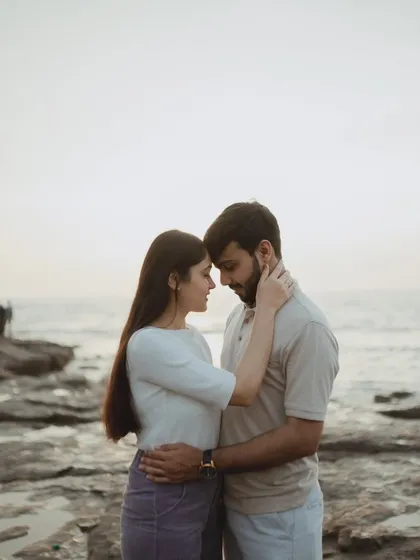 An intimate forehead-to-forehead pose on the rocky shores of Mumbai. This classic romantic shot captures the couple's deep connection with the sea as their witness.