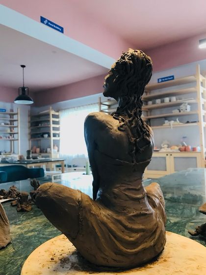 A back view of the "Naughty Girl" sculpture, showcasing the incredible detail in the hair and the musculature of the back.