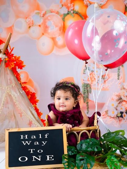 A chalkboard sign adds a personal touch to this six-month milestone session, announcing that this little one is "Half Way To ONE."