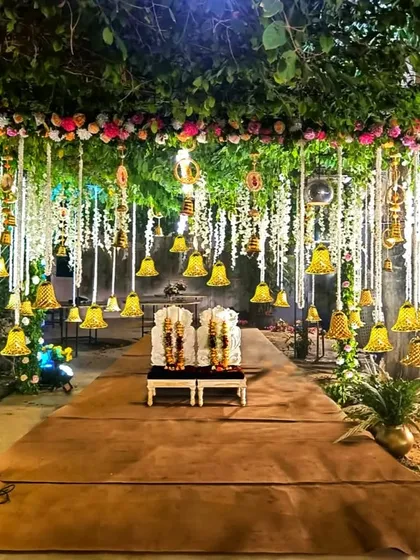 A wedding mandap should feel like a sacred garden, and for this nighttime ceremony, I created just that. The structure is enveloped in lush natural greenery and floral arrangements, with dozens of hanging bells and flowers illuminated to create a truly magical and romantic setting.