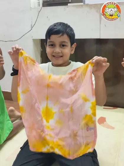 Exploring the science of natural dyes. This young artist proudly shows off a handkerchief dyed using turmeric and beetroot, learning about pigments found in nature.