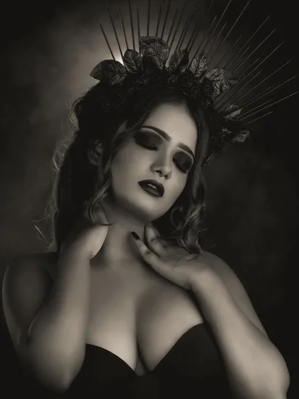 This black and white shot captures the texture of the makeup and the intricate details of the crown. The smokey eye and dark lip create a timeless, powerful character portrait.