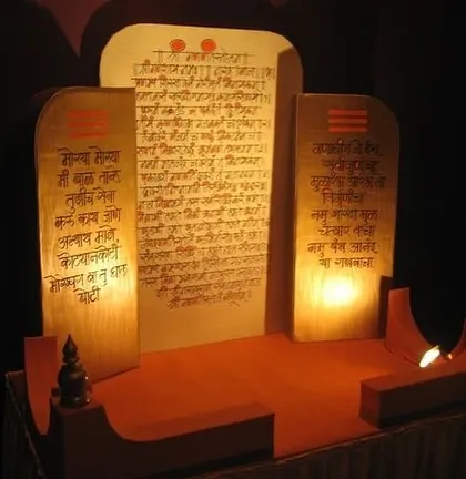 This image showcases a beautifully crafted Ganpati singhasan (throne) featuring panels with sacred Marathi verses. The soft, internal lighting highlights the script and creates a serene atmosphere for worship.