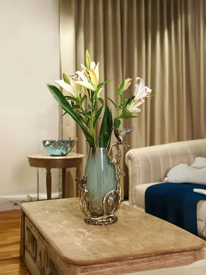 I love creating pieces where nature and art intertwine. This hand-blown glass vase is embraced by sculpted metal branches and birds, turning a simple floral arrangement into a captivating story for your coffee table or console.