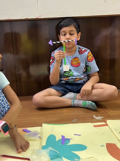 This young boy is completely focused on his experiment, learning about airflow and direction with a simple paper arrow and straw.