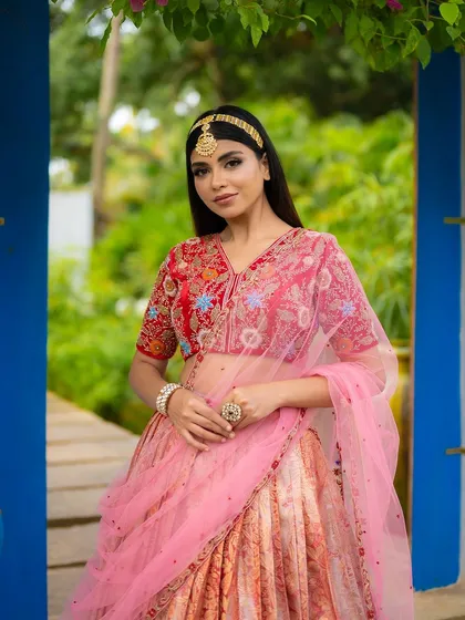 A beautiful portrait of a model in a designer half saree, framed by blue doorways. The composition uses color and architecture to create a visually interesting shot.