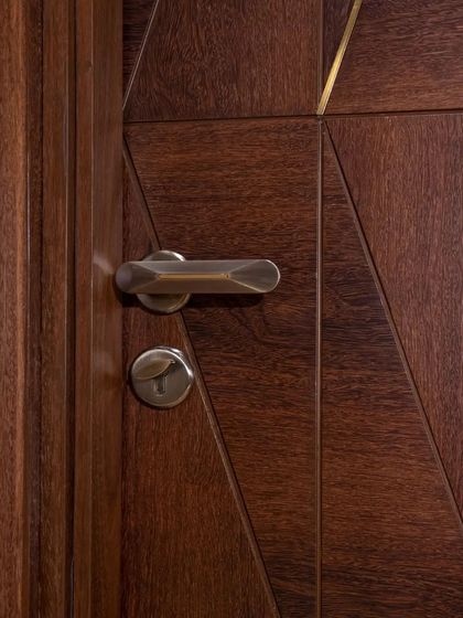 A close-up of the hardware on the Natural Brown Sucupira Veneer door, showing how it integrates with the geometric metal trims.