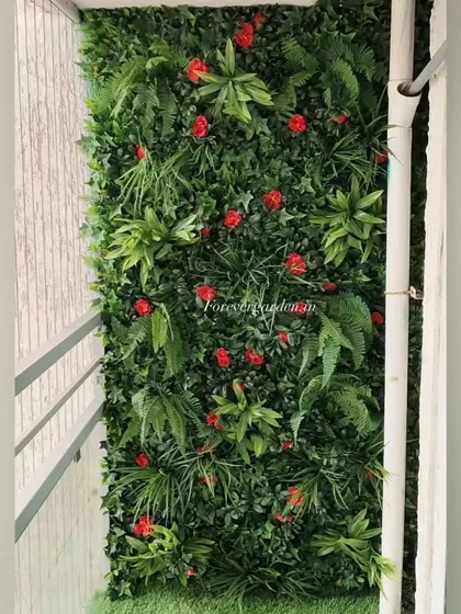 A balcony green wall with a mix of ferns and vibrant red flowers, adding a tropical feel to the space.