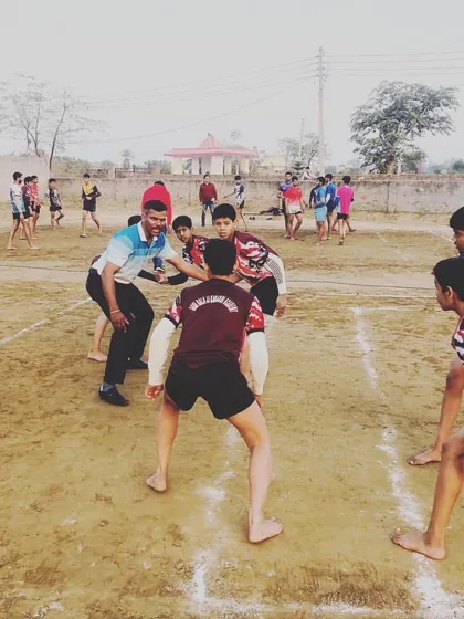 Leading by example. I am demonstrating a defensive stance to our junior players during a practice match on the mud court.