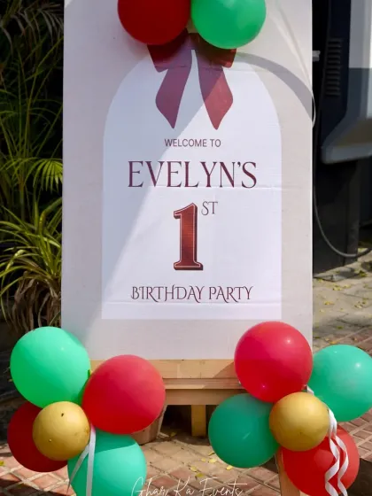 A festive welcome sign for a Christmas-themed first birthday. The red, green, and gold balloons match the holiday theme and create a cheerful entrance.