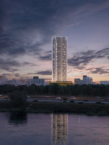 The same sustainable residential tower viewed at dusk, with its reflection in the water, highlighting its slender form and elegant presence.
