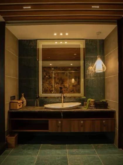 A direct view of the vanity area, showcasing the elegant vessel sink, backlit mirror, and the warm, ambient lighting from the pendant and ceiling lights.