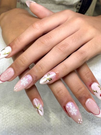 Winter wonderland on your fingertips. This festive set on long stiletto extensions includes delicate snowflakes, gold bows, and a cute reindeer design for the perfect holiday manicure.
