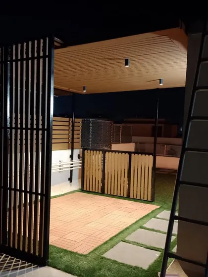 A view of the pergola-covered seating area at night. The downlights in the ceiling create a warm and intimate setting, perfect for enjoying the cool evening air.
