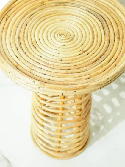 A top-down view of our coiled rattan pedestal stool. The spiraling pattern of the seat showcases the meticulous hand-craftsmanship that goes into each of our unique furniture pieces.