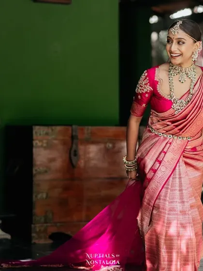 A bride in a flowing pink saree, her joyful movement captured as she walks on the verandah.