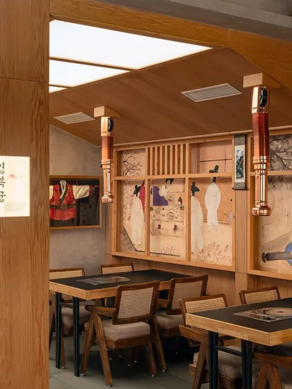 The interplay of light and material is key in this view of Seoul. The soft glow from the ceiling illuminates the rich wood tones and the intricate details of the artwork, creating a warm and refined dining setting.