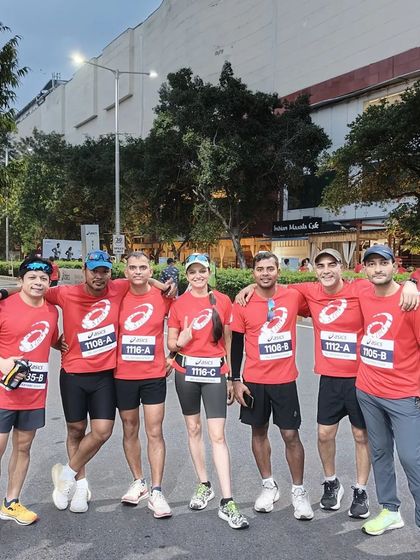 A group of our runners posing together after a training session. The matching red ASICS t-shirts create a strong sense of team identity.