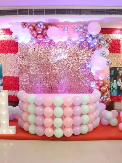 The main stage for a first birthday, with a rose gold sequin wall, a marquee number '1', and personalized photo displays.
