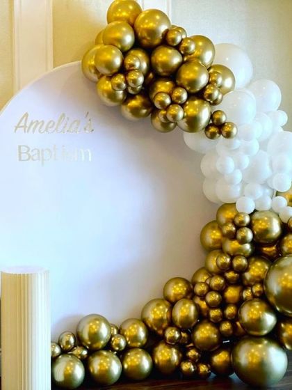 An elegant baptism decoration with a white and gold chrome balloon arch. The simple, clean design is perfect for a sophisticated and modern ceremony.