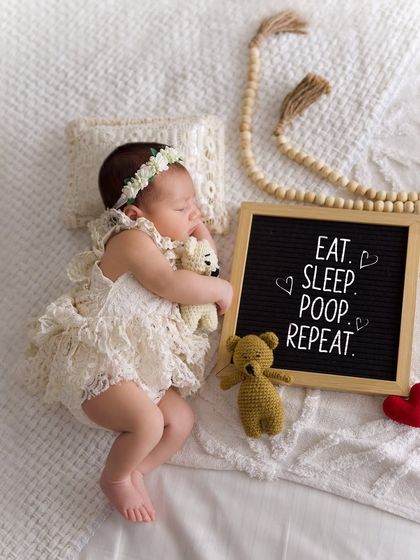 A fun and honest take on newborn life. This sleeping baby is next to a letter board that reads "Eat. Sleep. Poop. Repeat," adding a touch of humor to the adorable scene.