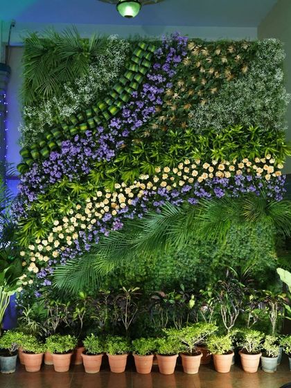 A full view of the vertical garden wall under event lighting. The spotlights enhance the different textures of the leaves and flowers, making it a dynamic and visually interesting feature.