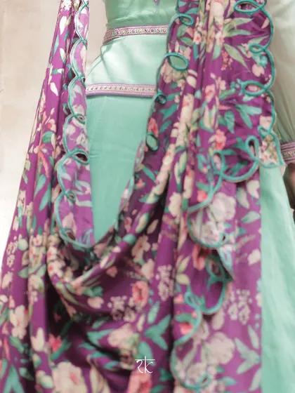 A detail shot of the floral printed dupatta with its unique cut-work border, adding a modern and artistic flair to the turquoise lehenga.