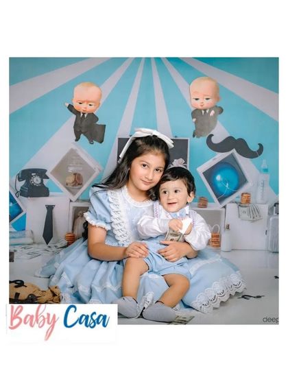 A brother and sister duo looking adorable in their matching light blue and white outfits for a 'Boss Baby' themed photoshoot. We love creating these memorable looks.