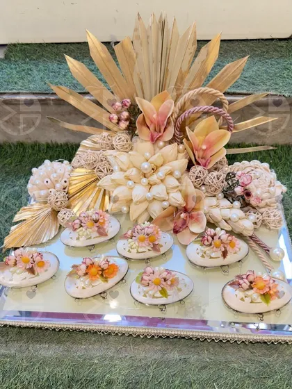 A neutral-toned wedding hamper with beautiful handcrafted elements. This tray features small, decorated plates and is adorned with dried flowers and sola wood art, perfect for a rustic or bohemian wedding theme.