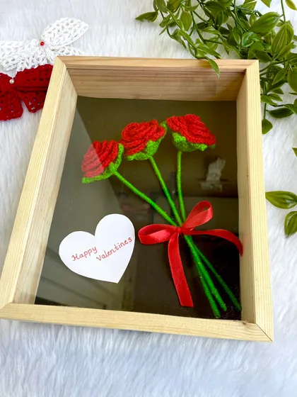 A classic arrangement of three red roses, tied with a red ribbon and framed in a shadow box. This is a timeless and romantic piece of handmade art.