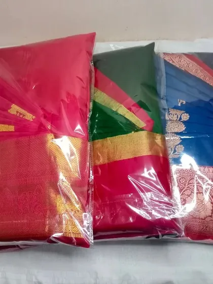 A set of three silk sarees, pleated and packed, ready to be sent back to the client.