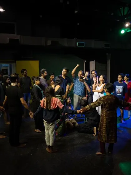 Performers and audience members holding hands in a circle on our stage, embodying the spirit of community and shared experience.