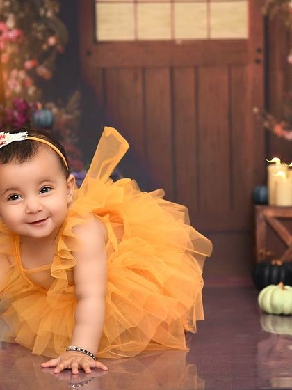 A sweet crawling pose in our autumn-themed setup. The soft, reflective floor adds a touch of magic to the scene.