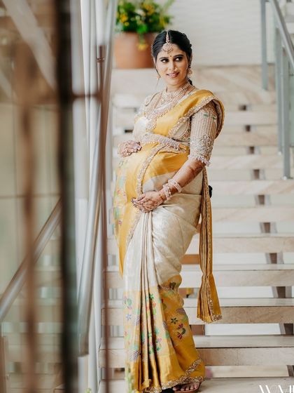 A full-length view of me at my baby shower, showcasing the beautiful drape of my saree and my baby bump.