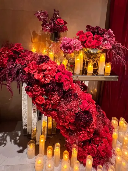 The decor featured opulent details like crystal chandeliers draped in red velvet, cascading floral arrangements, and candelabras that added to the romantic, high-end feel of the celebration.