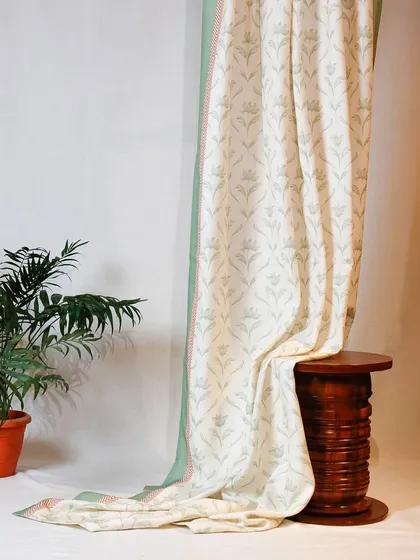 This beautiful curtain showcases a classic block-printed floral motif on a light, natural fabric. The soft green and pink border adds a subtle touch of color, framing the design perfectly.