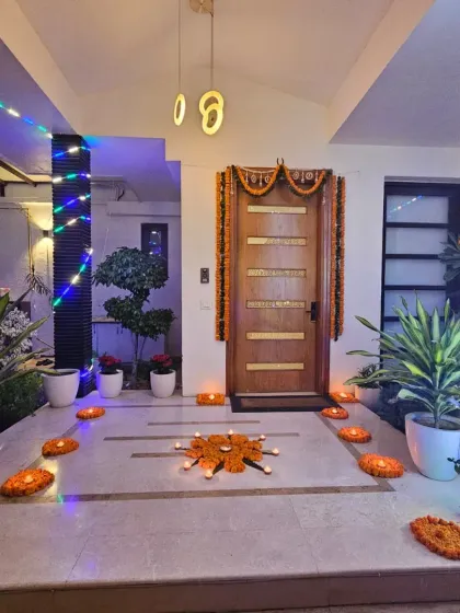 Another view of the entrance decor for a spiritual gathering. The combination of marigold torans on the door, rangoli-style flower arrangements on the floor, and soft lighting sets a peaceful and festive tone right from the moment guests arrive.