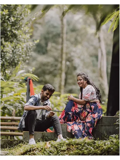 A candid shot of a couple sharing a laugh during their pre-wedding shoot in a relaxed, natural setting.